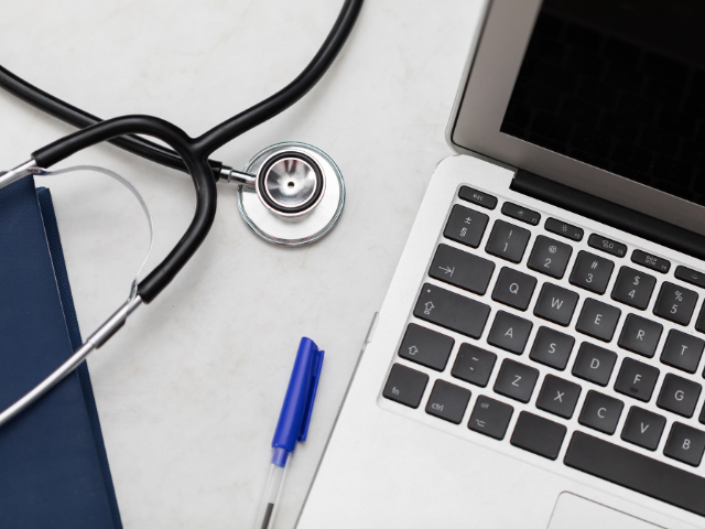 A stethoscope sitting next to a laptop