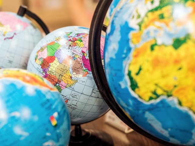 Four classroom globes on a desk.