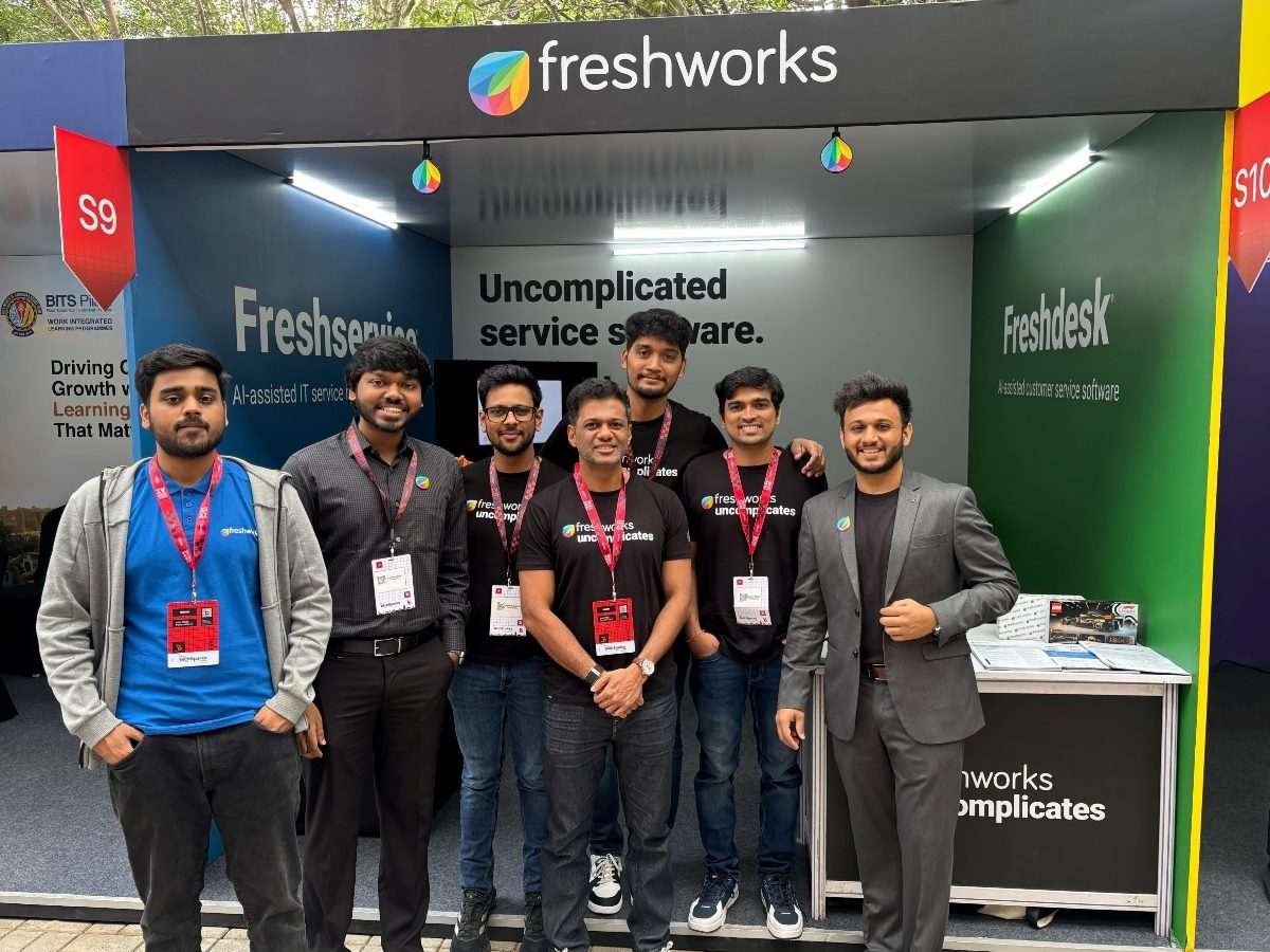 Freshworks team members stand together at a company booth showcasing Freshservice and Freshdesk, promoting the brand’s “Uncomplicated Service Software” message during an industry event.