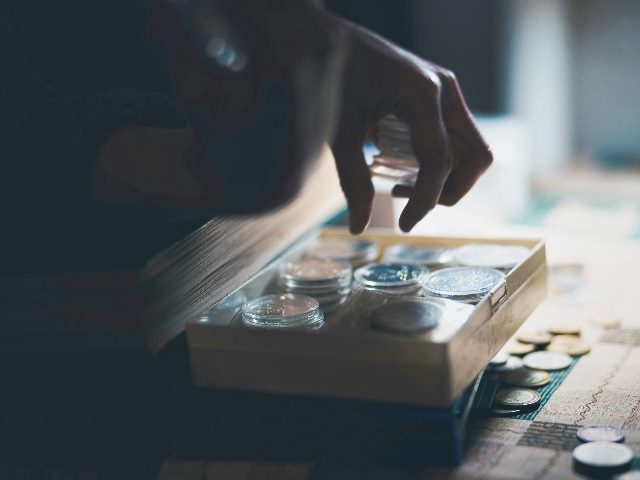 A hand dipping into a container filled with coins.