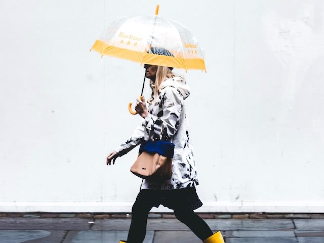 woman walking up the street under a see-through umbrella
