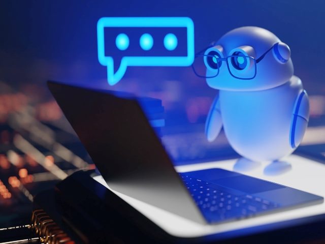 Cute Conversational copilot AI robot stands on a laptop flooded with blue light with speech bubble on the left. A small pile of books sits on the left corner of the laptop next to the robot.