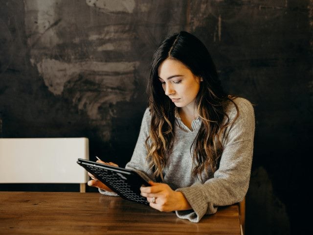 A person uses a tablet computer on a table.