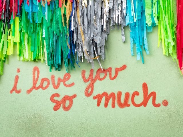 Famous green "I Love You So Much" mural in downtown Austin Texas with colorful confetti, representing an Amazon customer review. 