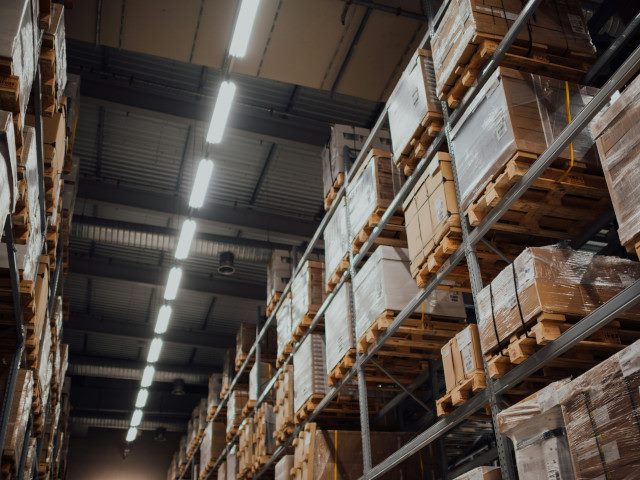Pallets of goods fill shelves in warehouse.