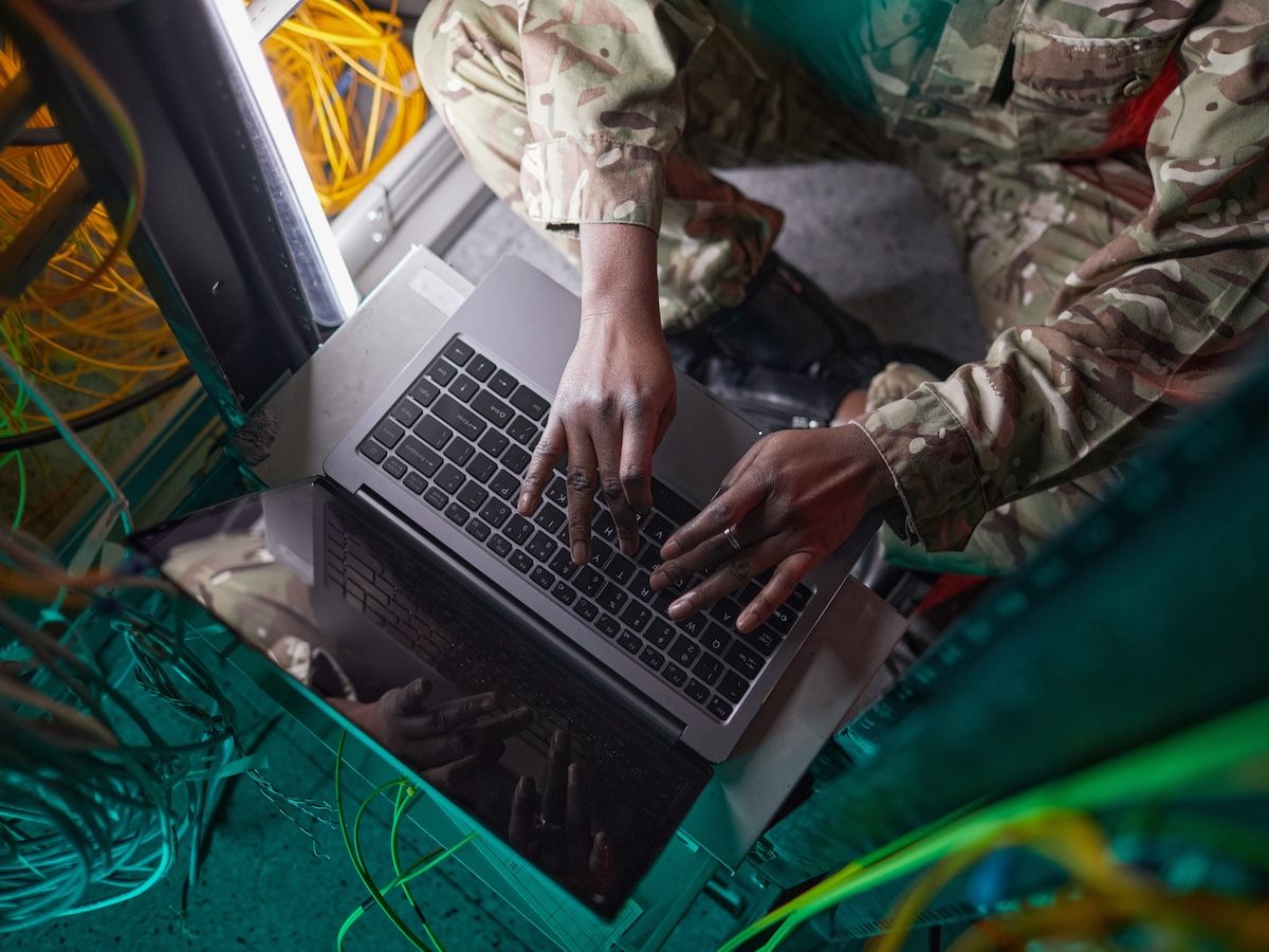 a person wearing military uniform while using computer in server room 