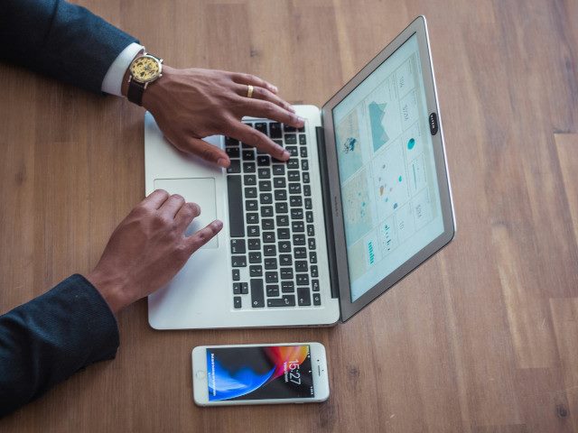 An employee works with a data dashboard on a laptop computer on a desk.