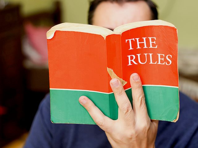 close up of an open copy of the book "The Rules" in someone's hand