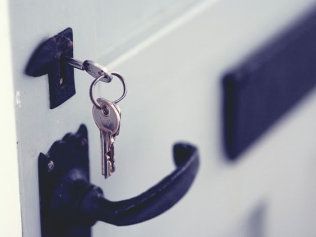 A key on a keychain hanging from a door lock
