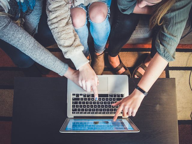 three co-workers looking at a laptop
