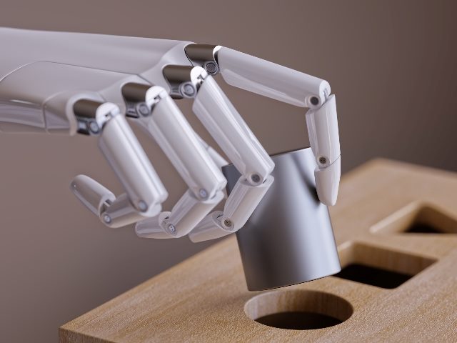 A white robot hand fits a round wooden peg into a round hole in wooden toy bench that also has triangle and square holes, suggesting  the importance of machine learning and generative AI in Marketing. 