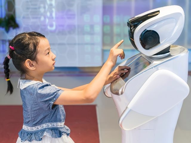 Young girl extends a hand to a robot. 
