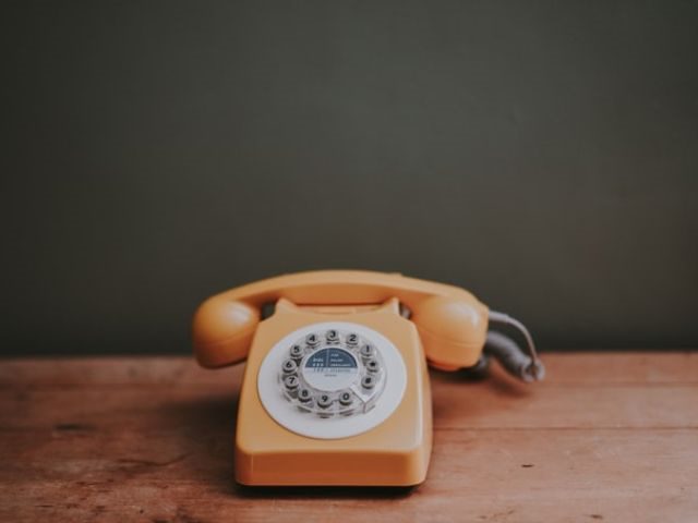 An orange rotary phone sitting on a table