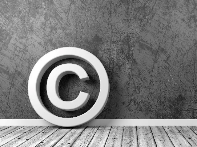 AI copyright symbol in white leans against a textured wall and sites on a wooden floor in grayscale in piece about AI copyright infringement.