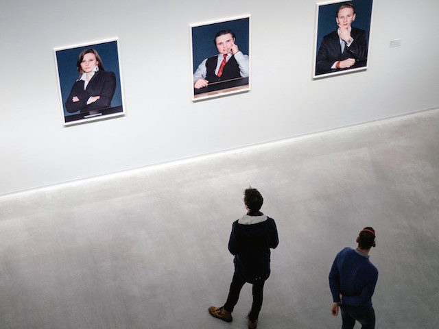 two people standing in front of paintings in a gallery