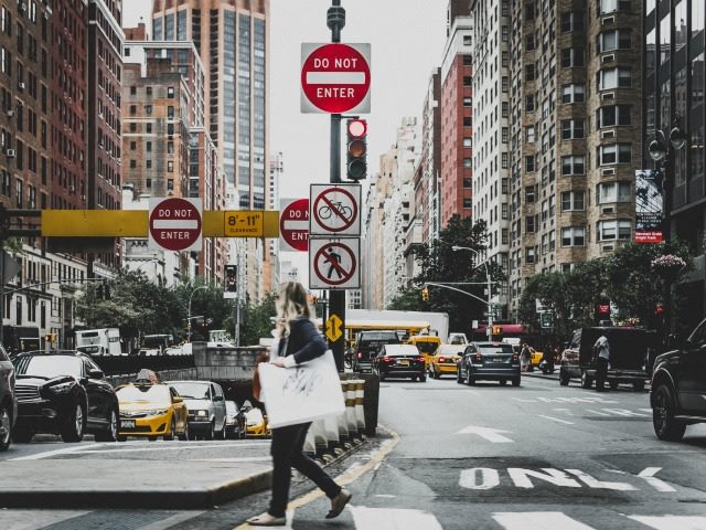 woman with shopping bag crossing busy street