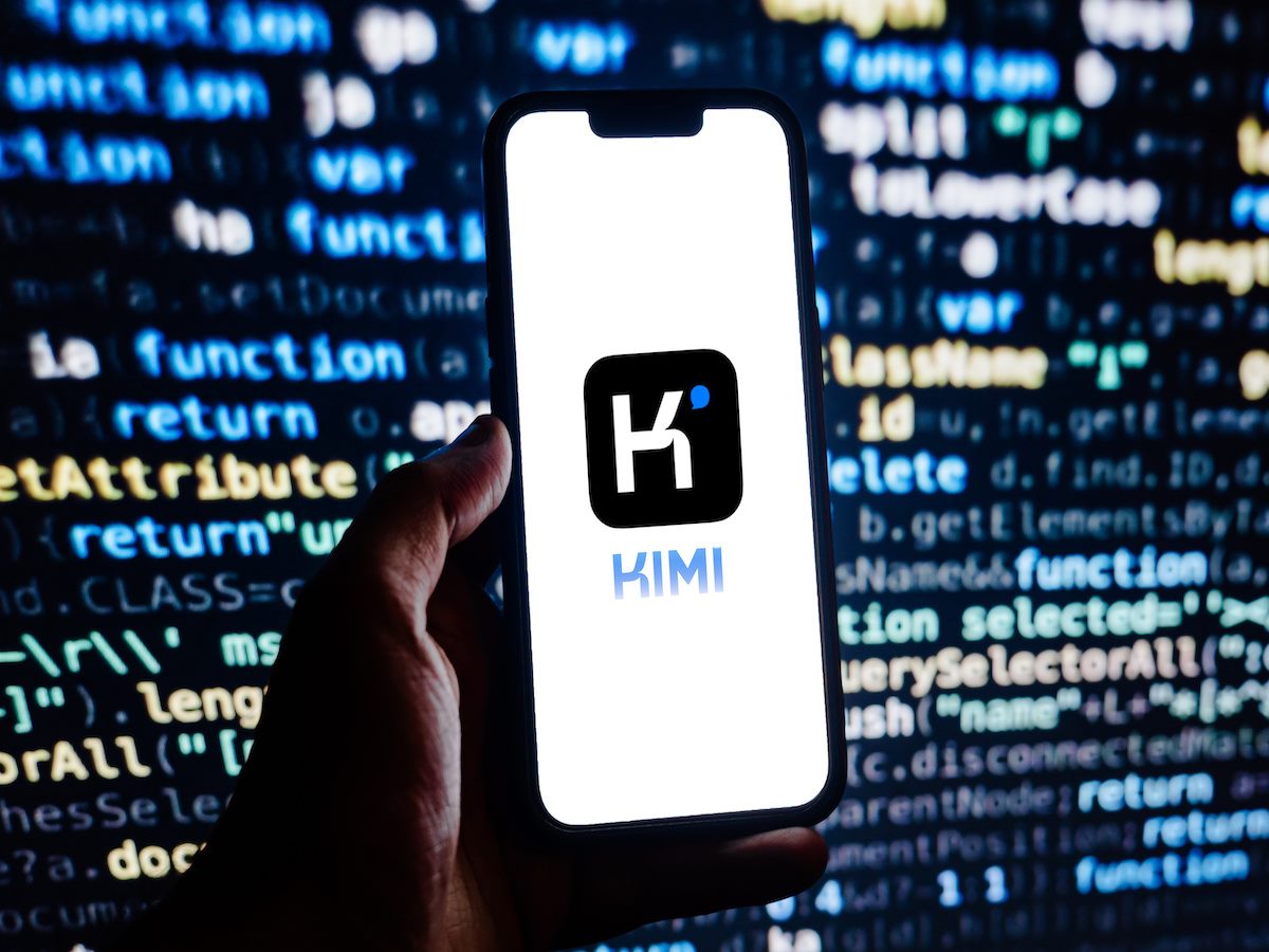Kimi chatbot logo on a smartphone in front of a screen full of code 