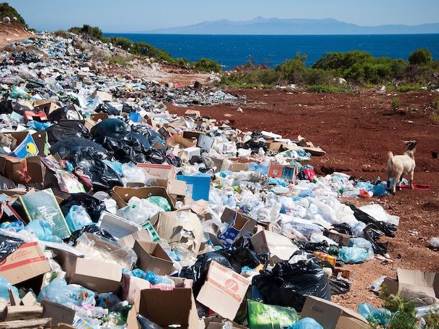 garbage dump in foreground, beautiful sea and mountains in background