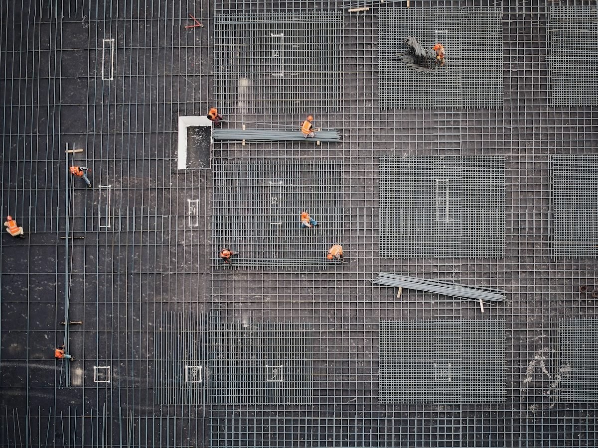 industrial construction site from above, workers visible on top of steel grates