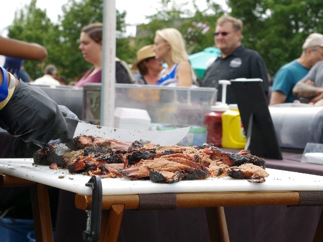 Customers wait as bbq beef is being sliced fresh from the fire.