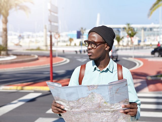 man holding a paper map looking confused