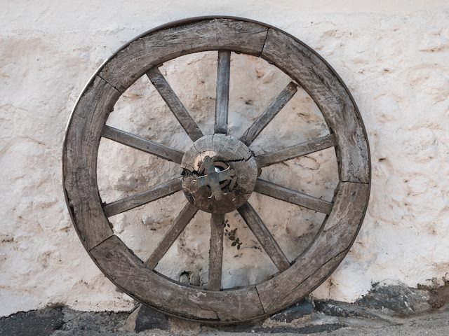 Old wooden wheel against a stone wall