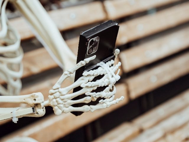Skeleton hands using a mobile phone.