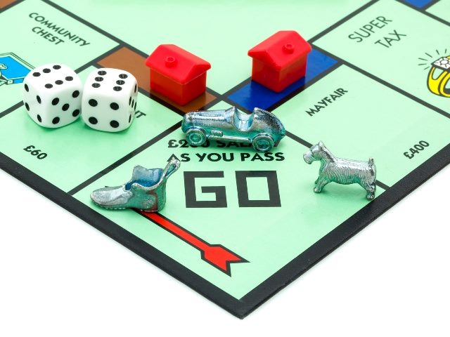 Monopoly game board with. two read houses and a dog, car and shoe playing pieces and two die with sixes showing.