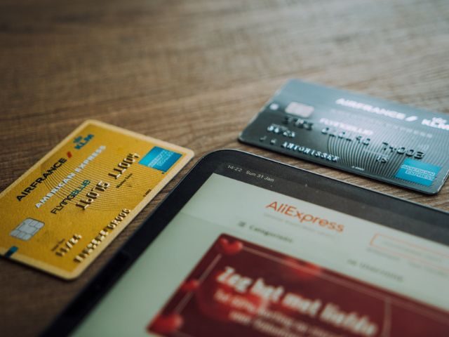 Two credit cards laid out next to a smart tablet with Ali Express pulled up on screen
