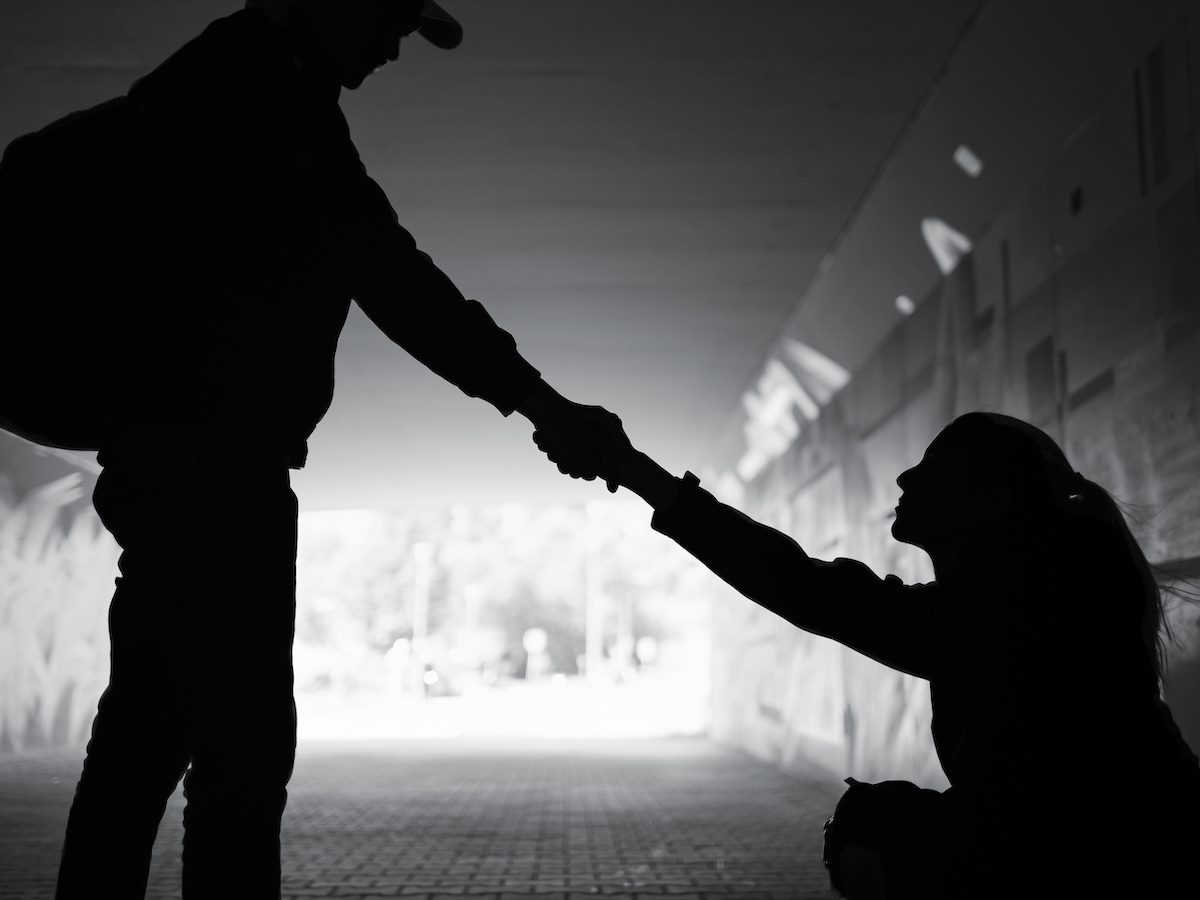 Man giving a woman help off the street