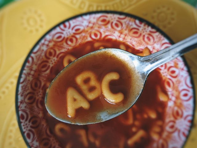 close up of a spoon full of alphabet soup, the letters A, B, C in the spoon
