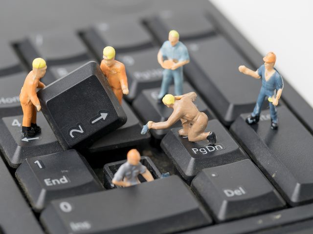 miniature figures assembling a keyboard