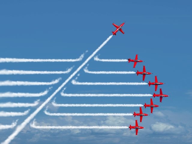 7 red jets fly in straight lines with white vapor trails following behind them and one red jet flying at an angle cuts through the vapor trails against a background of bright blue skies in piece about the  future of generative AI and  disruption. 