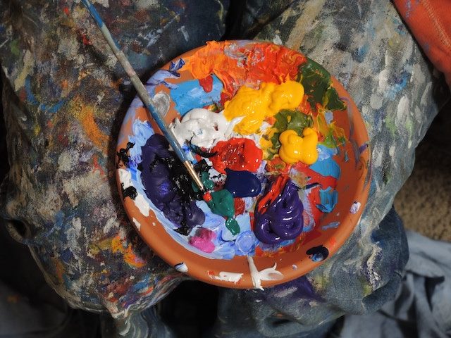 a palette covered in bright paint with a paint brush 