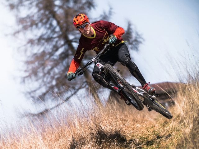 A mountain biker jumps in a field.