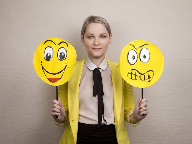 woman holding up happy and sad faces