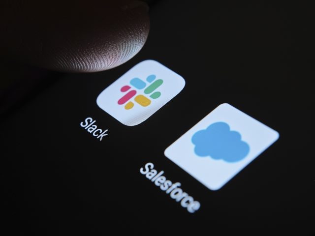 Salesforce and Slack apps on a phone screen with somebody's thumb next to the Slack app.