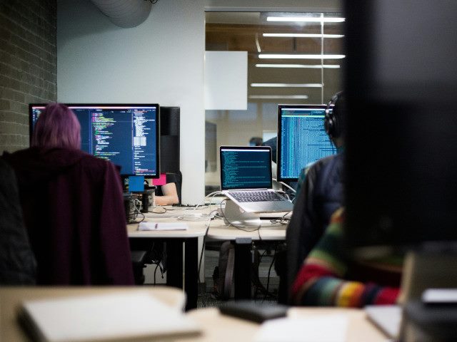 Software engineers write code on computers in an office.