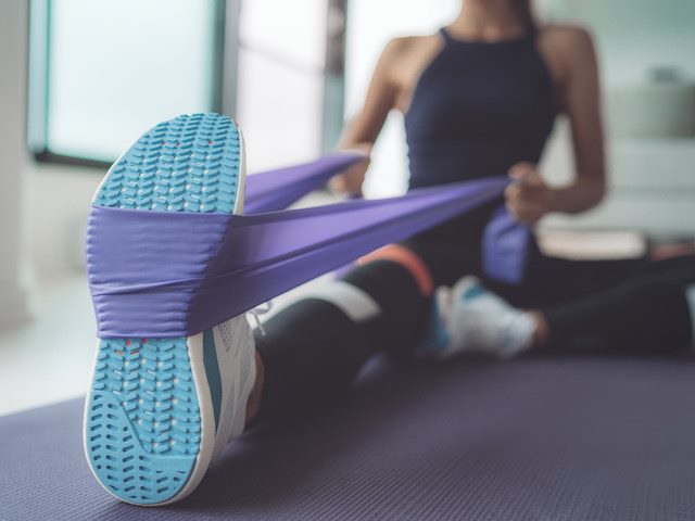 woman doing resistance band exercise on a yoga mat