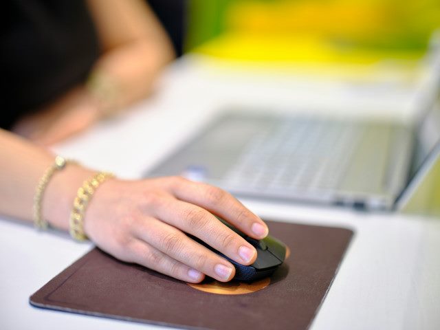 A person uses a computer mouse on a mouse pad.