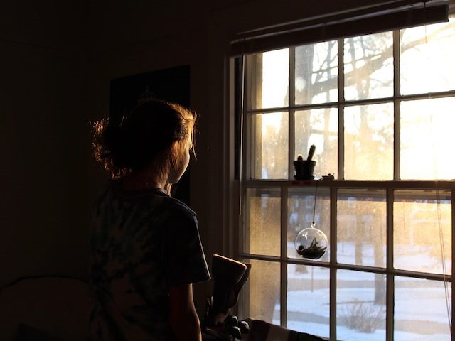 woman looking out the window at snowy scene