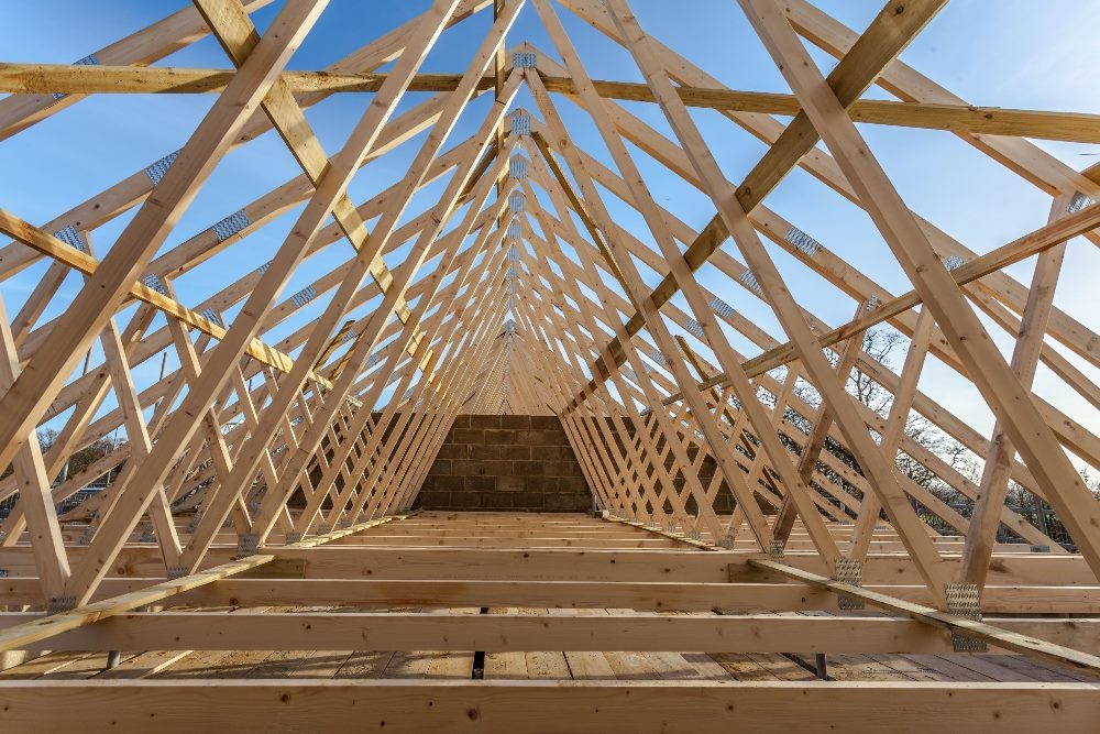 A wooden house truss framework against a blue sky in a piece about LLM agents.