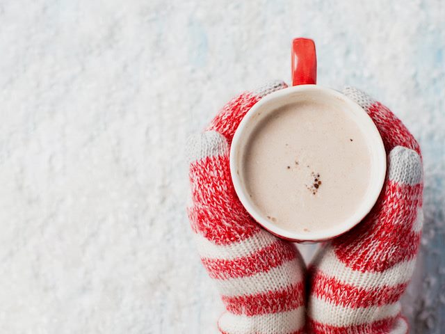 close up of someone's hands   in mittens, holding a cup of hot chocolate