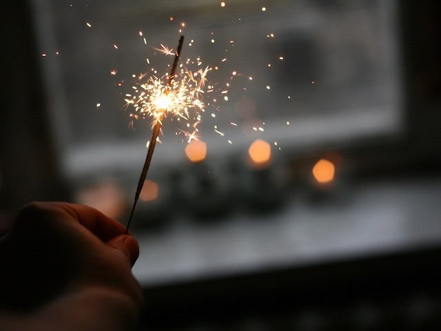 person holding sparkler near a window