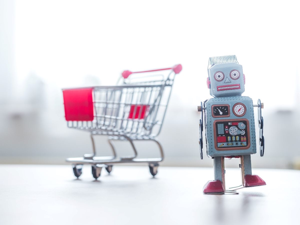 Online shopping algorithm concept with a toy robot on the desk, shopping cart in the blurry background.