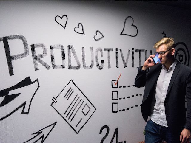 man on phone in front of "productivity" sign