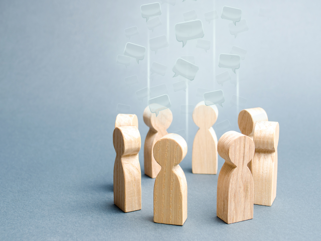 A speech clouds in the center of a circle of wooden people.