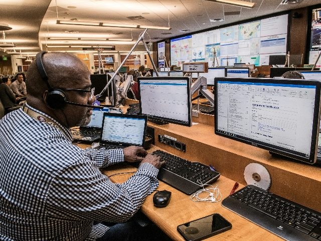 Man working at a busy contact center with headset on looking at terminals.