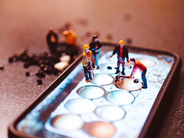 figurines working on an iphone as a construction site