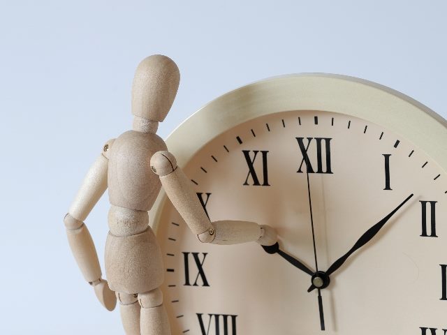 A wooden man turns the clock back, representing an historical look into artificial intelligence.